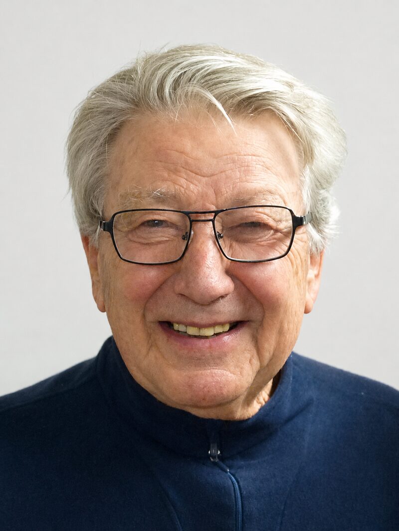Sepp Bergamin im Porträt – weisses Haar, Brille, lächelnd in dunklem Polo
